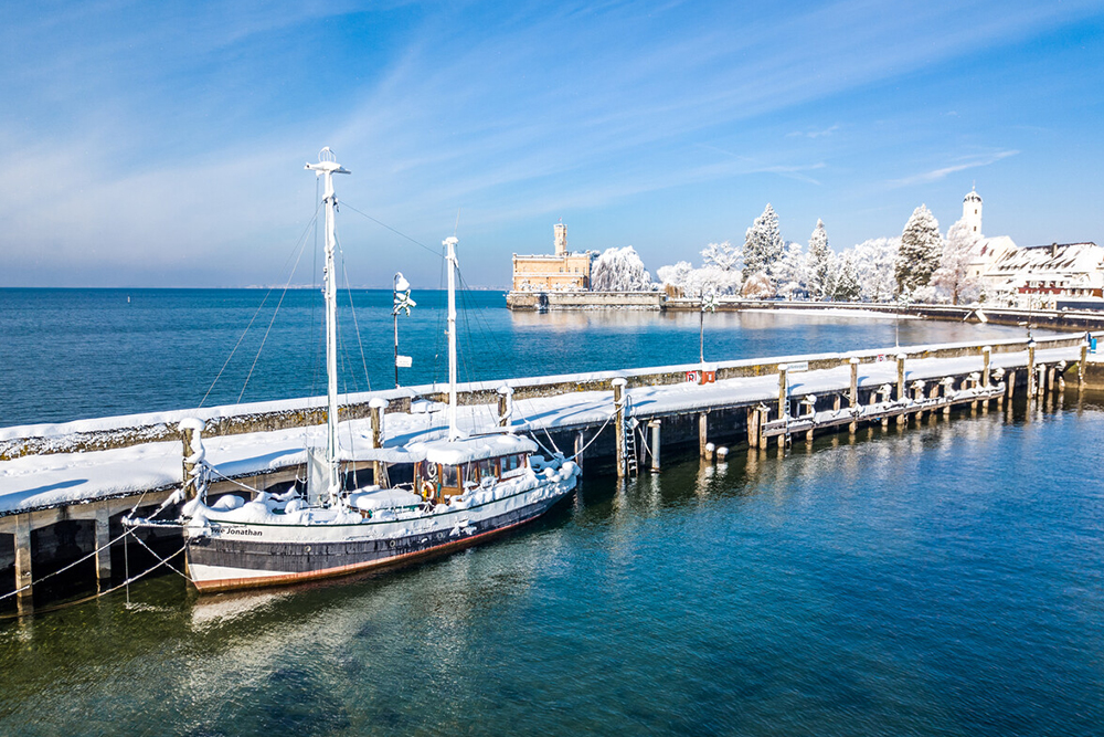 Sailing ship in the snowy harbor of Lindau on Lake Constance