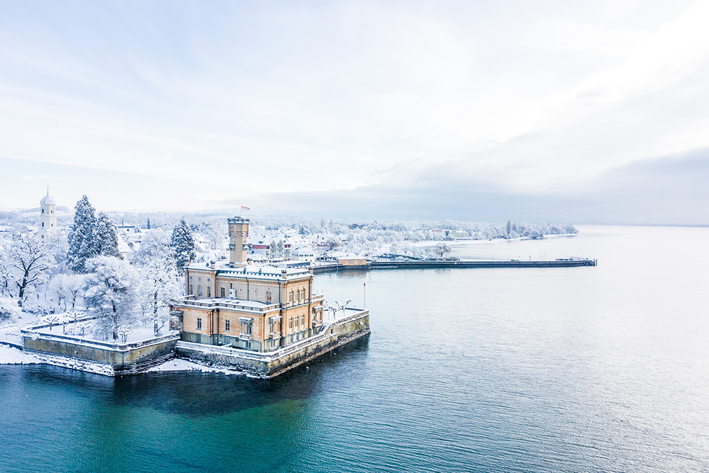 Historic harbor building on Lake Constance in a wintery snowy landscape